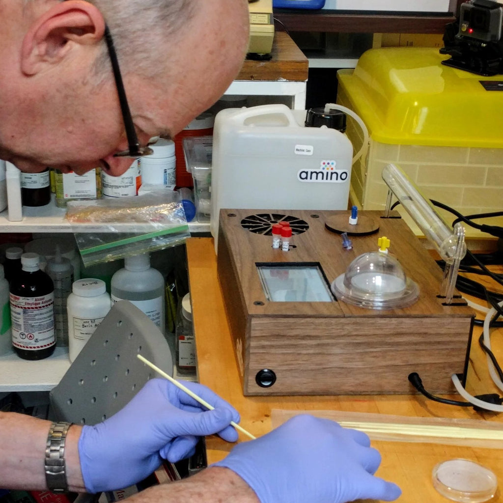 elderly man streaking bacteria at a DIYbioTO space, during a Genetic Engineering DIY biohacking virtual lessons by Amino labs STEM biotechnology kits and school laboratory equipment / home laboratory equipment / biohacking laboratory equipment